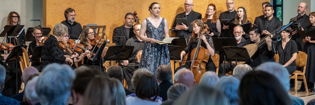 Soprano soloist in front of orchestra and chorus in concert